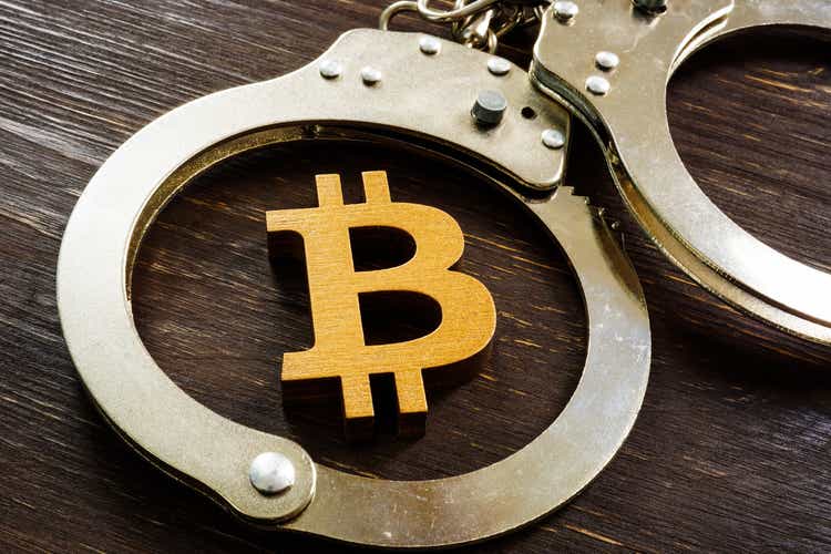 Fraud, ban and regulation of cryptocurrencies. Bitcoin sign and handcuffs.