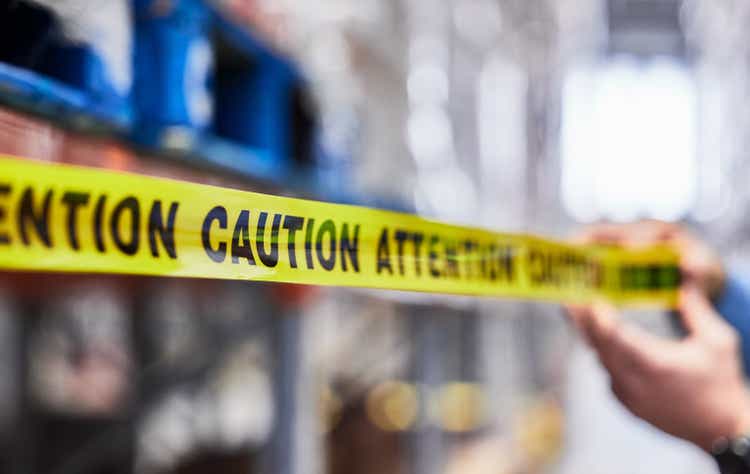 Shot of a unrecognizable man putting up tape in a warehouse