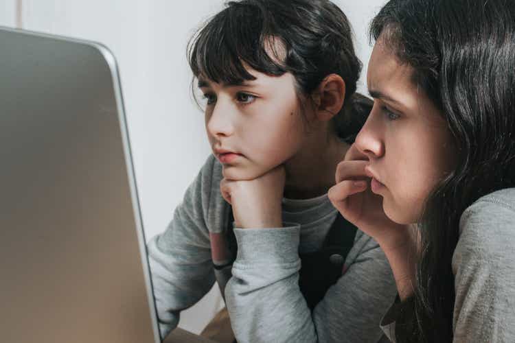 little girl and her sister looking at computer monitor