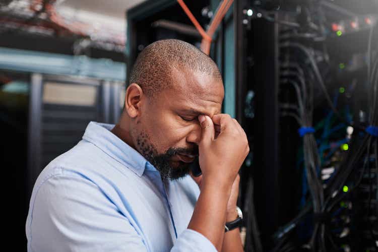 Shot of a mature man looking stressed out while working in a server room