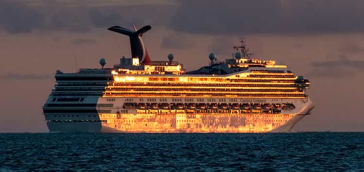 Carnival Conquest sailing by the coast of Belize at sunset. Sun reflecting off the ship"s side and making it look gold pleated. Cloudy sky in the background