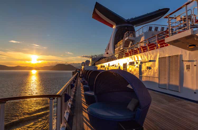 Carnival Legend sailing at sunset in one of the Alaskan Fjords. Sun setting down and mountains in the background. View from the deck in the aft of the ship