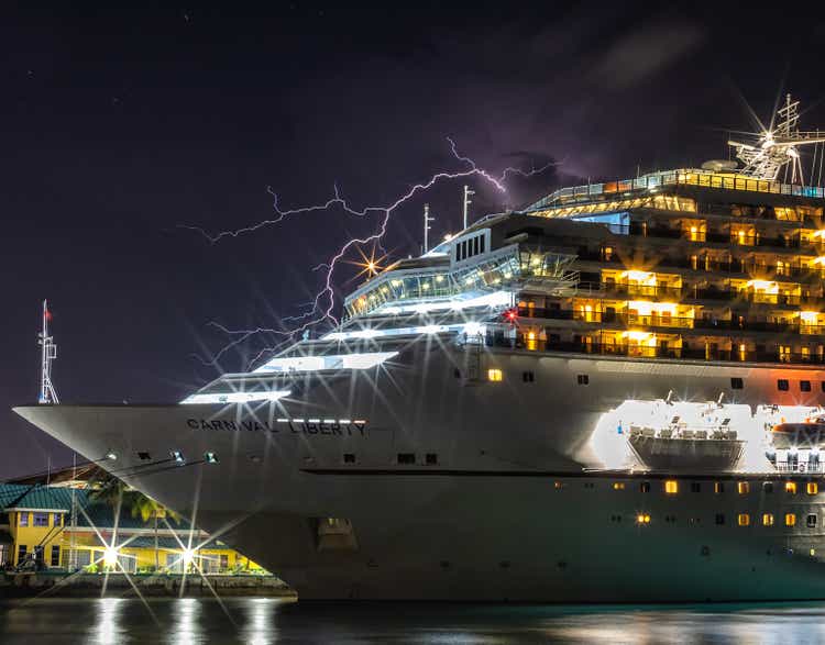 Beautiful Carnival Liberty cruise ship docked in Prince George Wharf at night. Cloudy sky with lightning in the background and above the ship. Long exposure