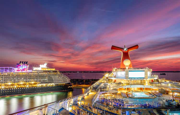 Carnival Liberty and Disney Dream cruise ships docked in Port Canaveral at sunset. Beautiful red-orange-blue sunset sky in the background