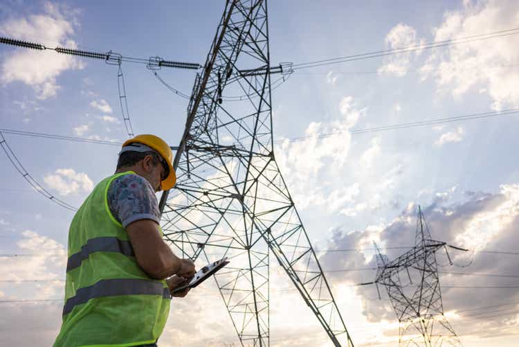 Engineers in front of power plant using digital tablet