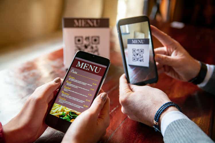 Couple at a restaurant scanning the menu with QR codes using their cell phones
