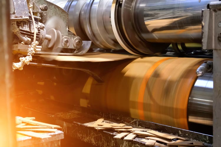 Ready-made cardboard boxes are moved in stacks along an automated packaging line. The strapping machine packs the stacks with thick white thread. Paper corrugated box factory.