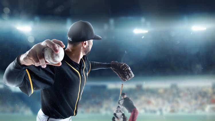 Professional baseball player in motion, action during match at stadium over blue evening sky with spotlights. Concept of sport, show, competition.