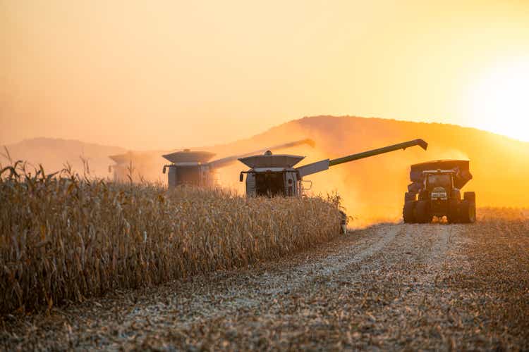 Kombinieren Sie die Ernte auf landwirtschaftlichen Feldern bei Sonnenuntergang.