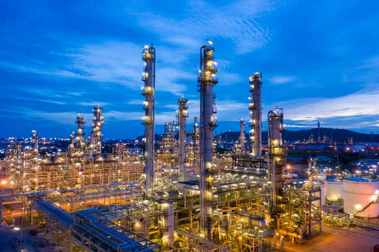 twilight landscape oil and gas LPG refinery factory with storage zone industry business import and export at night over lighting blue sky background aerial view from drone