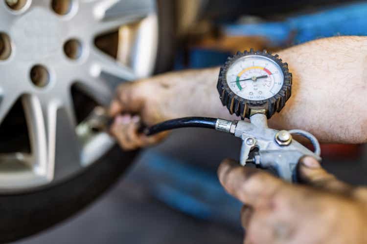 Close up of mechanic"s hand checking the air pressure of a tyre in auto repair service