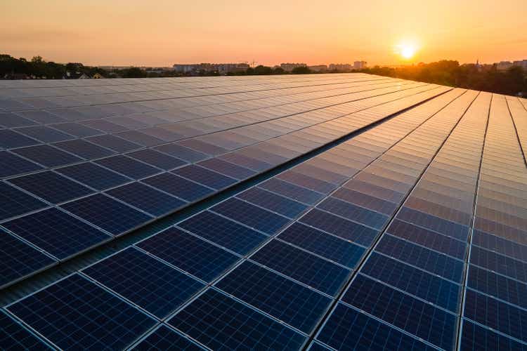 Des panneaux solaires photovoltaïques bleus ont été installés sur le toit du bâtiment pour produire de l'électricité écologique propre au coucher du soleil.  Concept de production d'énergie renouvelable.