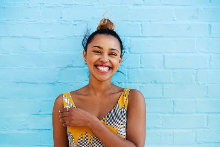 Woman laughing in front of blue wall