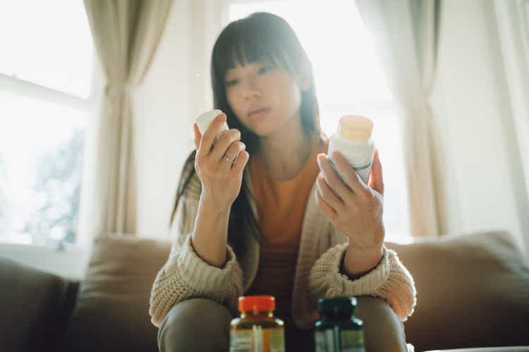 Asian woman choosing between supplements