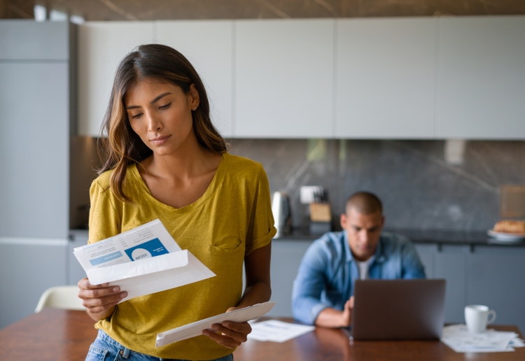 Woman at home looking worried getting bills in the mail