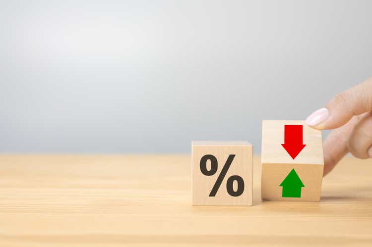 Interest rate financial and mortgage rates concept. Hand flip wood cube change arrow down to up. Wooden blocks with percentage sign and down arrow. copy space, gray background