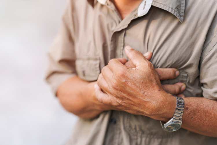 Close-up of an elderly man"s hand held his chest in pain. Concept of heart disease.