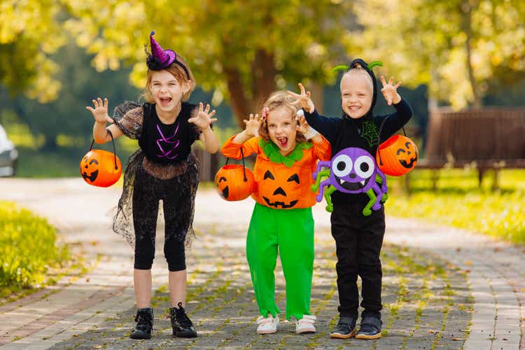 Three kid with a basket for sweets making grimaces on Halloween holiday outdoor