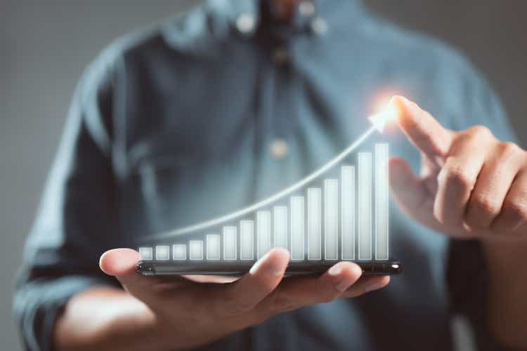 Business man holds a mobile phone and displays a graphic graph showing statistics of profitable graphs, ideas of growth planning and business strategy to see trends in good business.