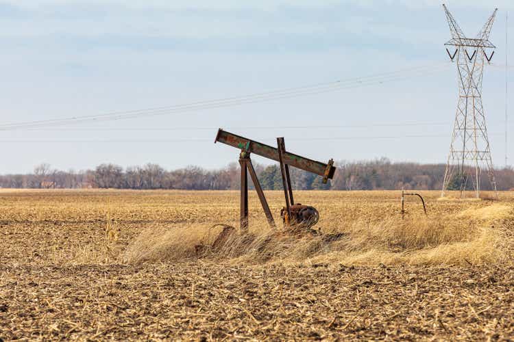 Old, orphaned oil well pump in farm field. oil well abandonment, decommission, and oil production concept