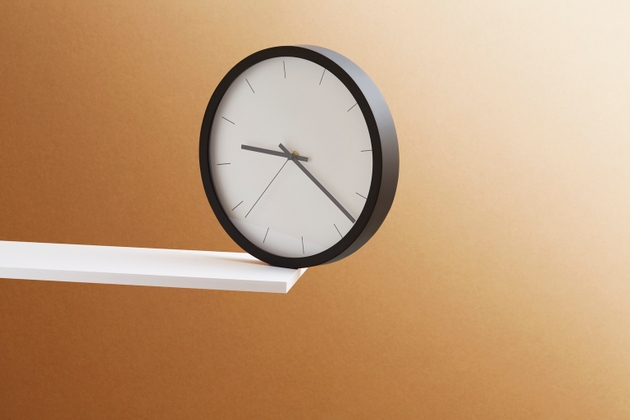 A clock balanced on the edge of a shelf