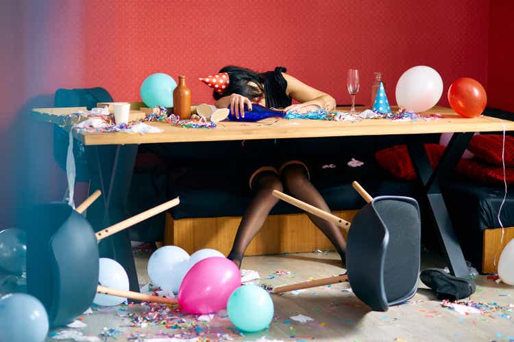 Young woman with sleeping at table in messy room after birthday party