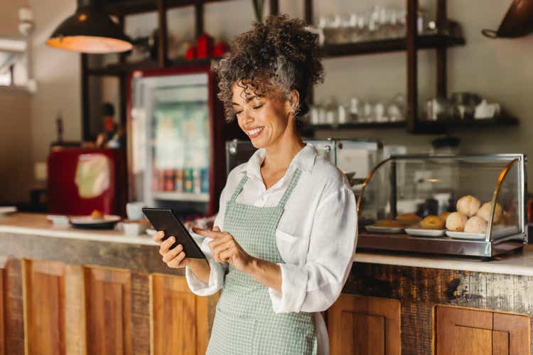 Happy cafe owner running her business on a digital tablet