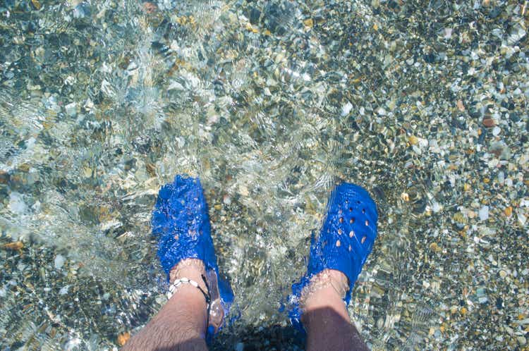 Male wearing blue clogs beside the beach