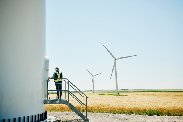 Wide shot of engineer preparing to enter wind turbine for inspection