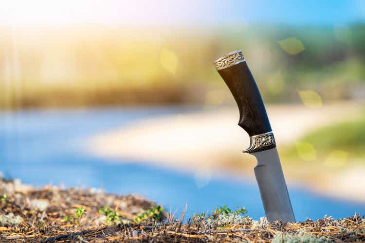 Matching knife on the banks of the taiga river. Accessories for hike.