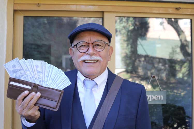 Senior businessman showing abundance with full wallet