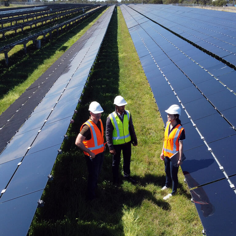Multiracial Group Of Three Engineers Surrounded By Solar Panels