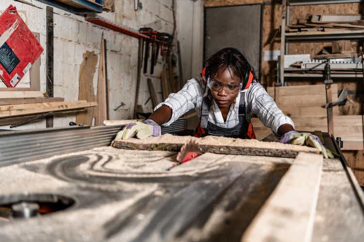 Photo of one African-American female carpenter using circular
