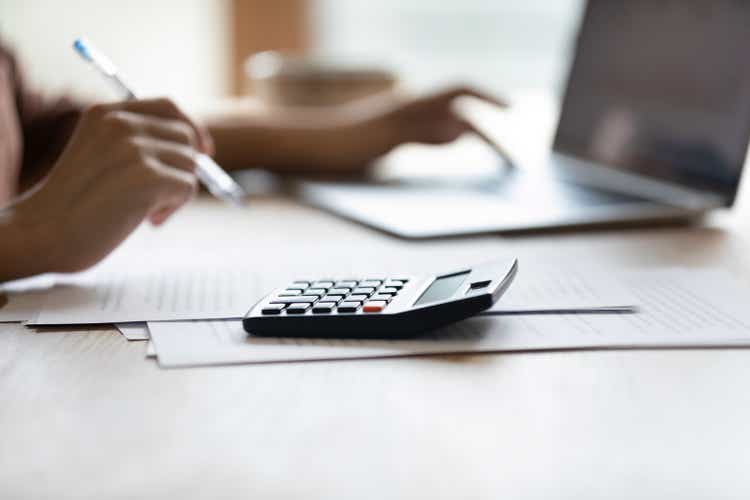 Closeup of female bookkeeper work at desk on calculator laptop