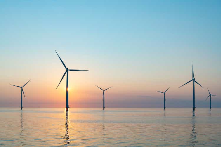 Wind turbines in an offshore wind park producing electricity during sunset.