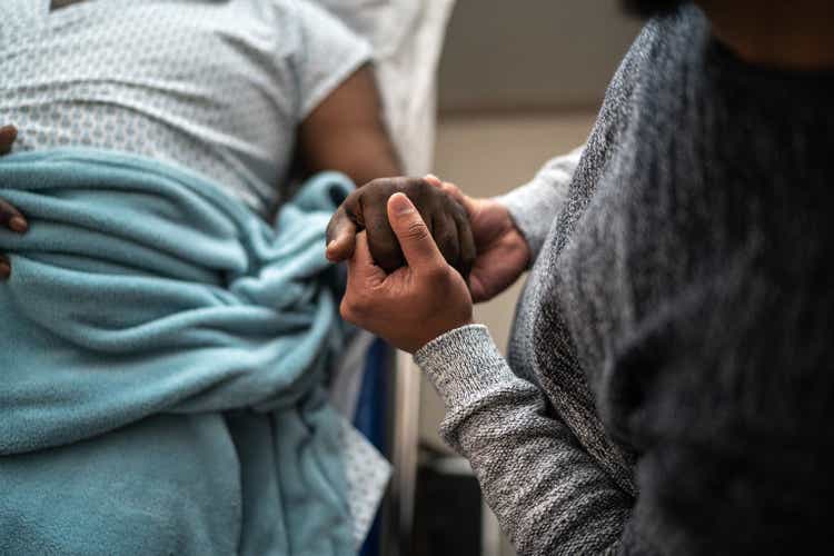 Son holding father"s hand at the hospital