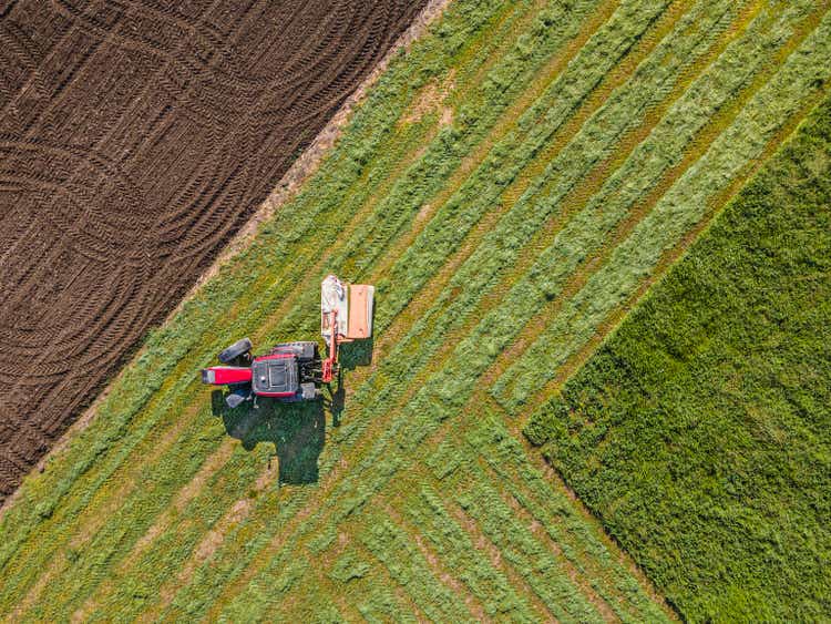 Aerial view of tractor mowing alfalfa. Springtime agriculture.