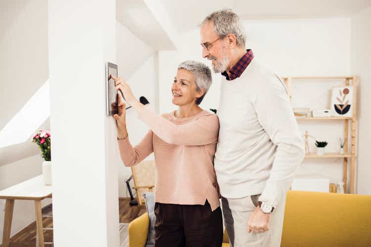 Happy senior man and woman using a smart system at their house