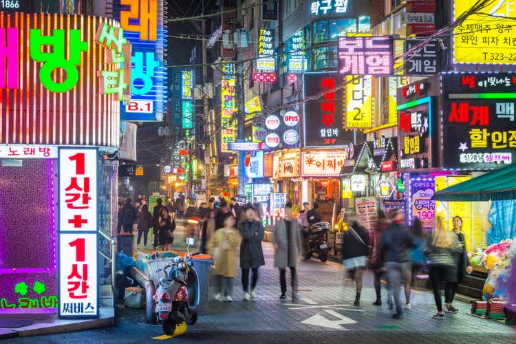 Seoul people walking through neon drenched night streets Sinchon Korea