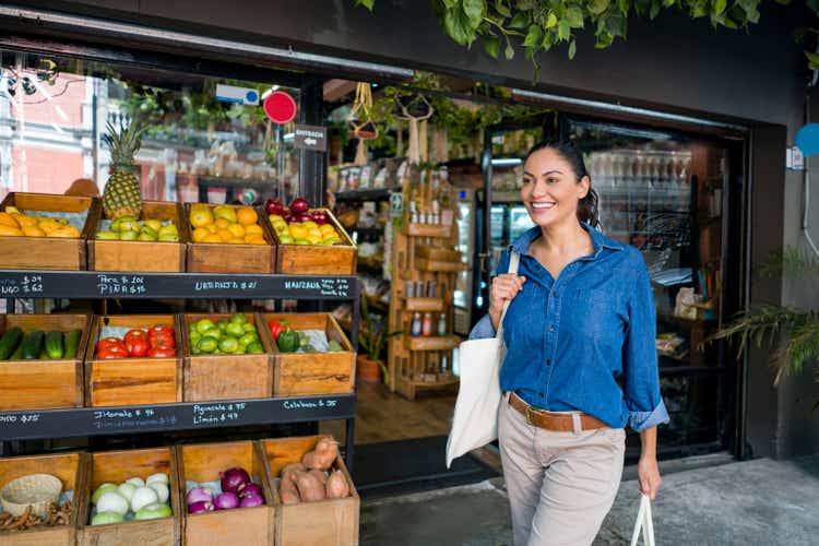 Happy woman shopping at the grocery shop using reusable bags