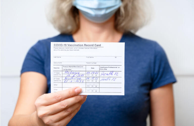 Vaccinated young woman showing COVID-19 Vaccination Record Card
