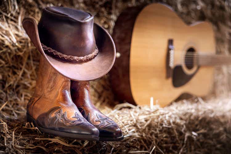 Cowboy hat guitar and boots in barn, country music festival live concert or rodeo background