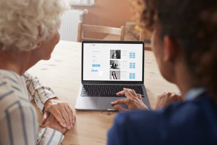 Nurse teaching woman booking online appointment