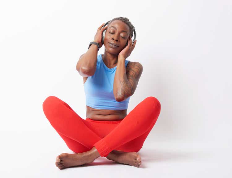 Mature woman wearing headphones, day dreaming lost in sound