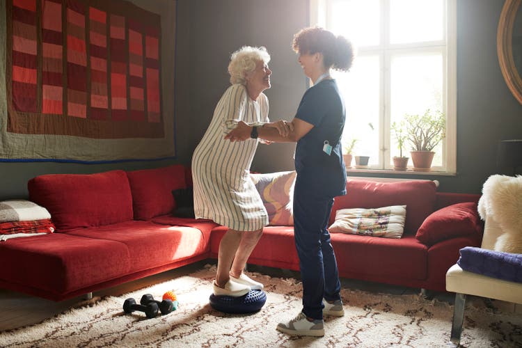 Woman taking support of caregiver while exercising