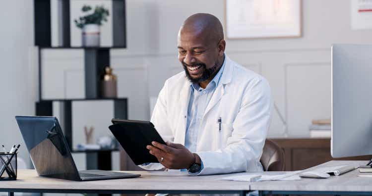 Shot of a male doctor using his digital tablet in his office