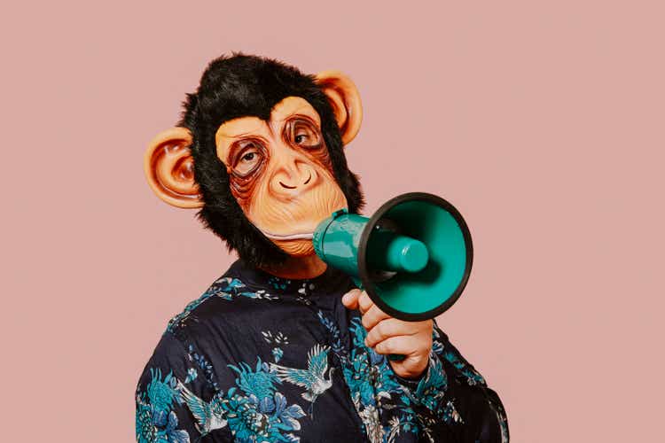 man wearing a monkey mask speaks into a megaphone