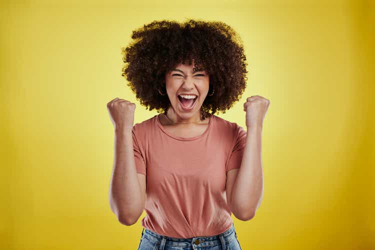 Studio shot of an attractive young woman looking excited against a yellow background