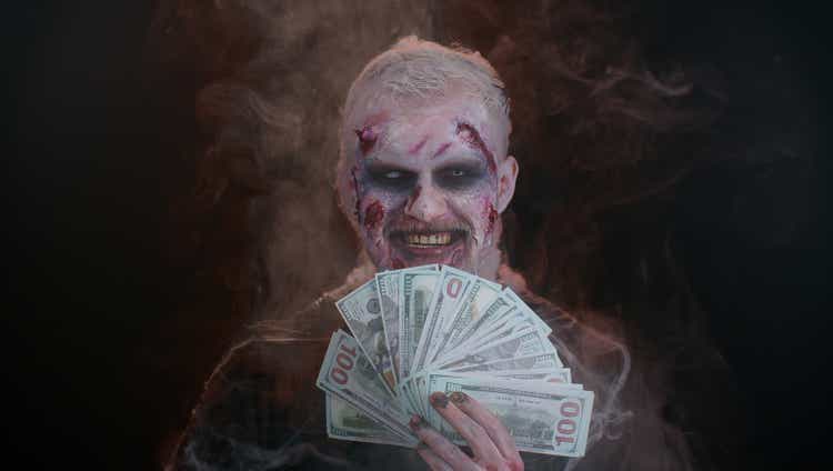 Scary sinister Halloween zombie wounded undead man with money dollar cash banknotes smiles terribly