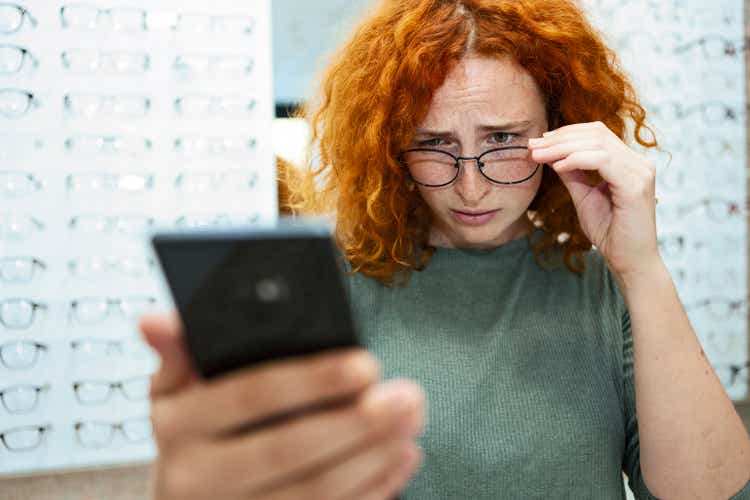 Redhead young woman with eyesight problems trying to read